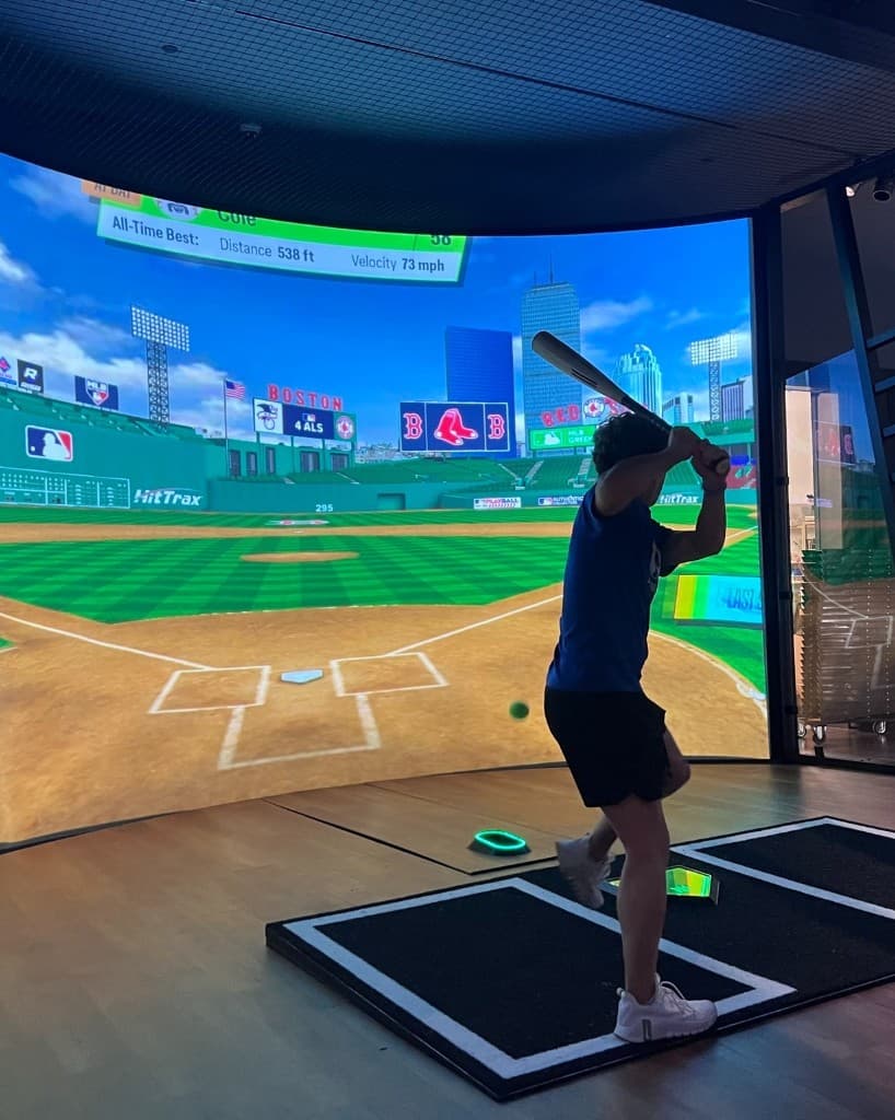 Guest swinging in a high-tech batting bay at Home Run Dugout in Katy, TX